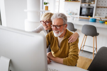 Cheerful senior couple using technology devices and having fun at home