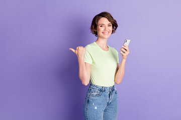 Profile side view portrait of nice cheerful girl holding in hands using device showing copy space ad look isolated over violet color background