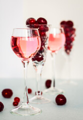 transparent glasses of pink gin infused with cranberry on light background, crystal glasses of spirits drinks with berries, a row of cherry liquor or any red alcoholic cocktail, minimalism