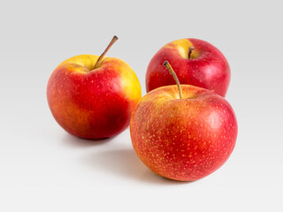 Three ripe red apples on a light background