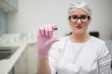 close-up of a female doctor holding medicine in pink disposable gloves in the clinic office