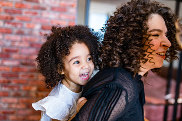 curly hair cute little mixed race baby in mothers hands in cozy room