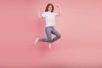 Fototapeta na wymiar Photo of active girl jump high up raise fists wear casual clothes on pink background