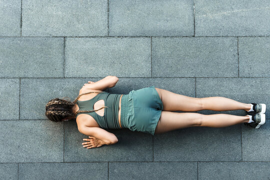 Athletic woman is doing push-ups during calisthenic workout on a street