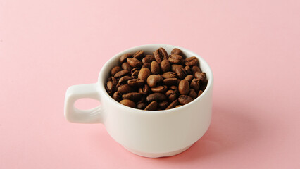 Coffee beans in white cup on soft pink background