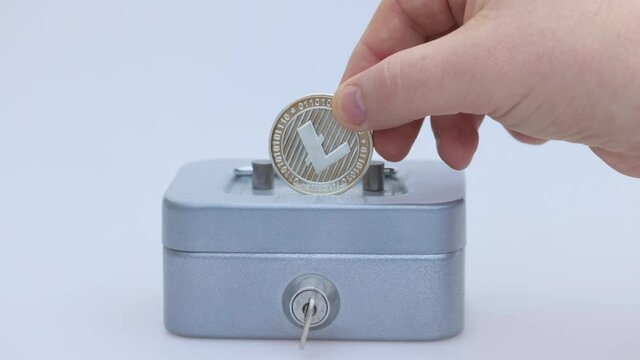 Little saving vault, hand holds silver LTC Litecoin virtual money. Cryptocurrency, business and saving concept. High quality photo