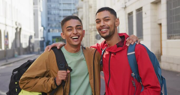 Happy mixed race gay male couple embracing in the street