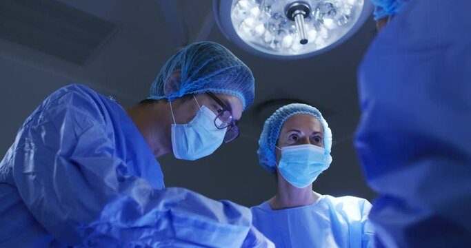 Diverse surgeons wearing surgical caps and face masks in operating theatre in hospital
