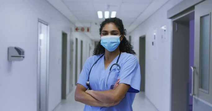 Portrait of asian female doctor wearing face mask and scrubs standing in hospital corridor