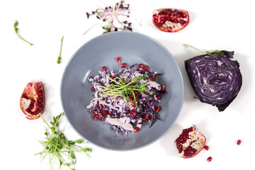 Top view of modern beautiful plate with delicious purple cabbage salad and composition vegetables on white background. Concept of cooking tasty salad with fresh vegetables.