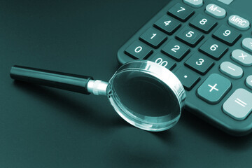 Calculator and magnifying glass on table.
