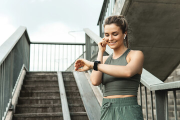 Athletic woman using smartwatch during her fitness workout on city street