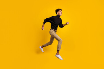 Fototapeta na wymiar Full size profile photo of optimistic nice brunet guy run wear black sweater trousers sneakers isolated on yellow background