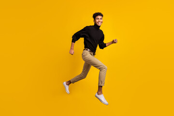 Fototapeta na wymiar Photo of sweet pretty dark skin man wear black sweater eyewear running jumping isolated yellow color background