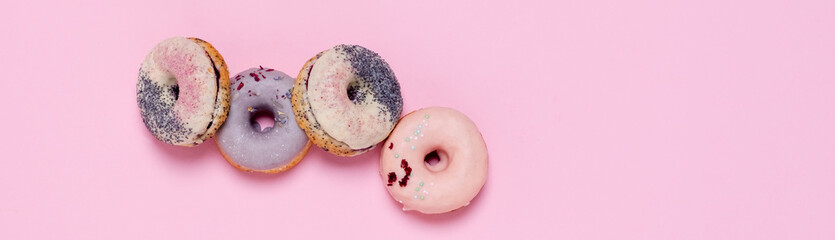 Tempting donuts dessert with iceing and sprinkles. Sweet sugar round doughnuts of different flavours. Top horizontal view copyspace. Healthy diet and junk food