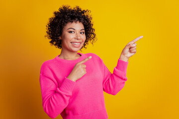 Portrait of cheerful pretty girl indicate finger copyspace isolated over yellow color background