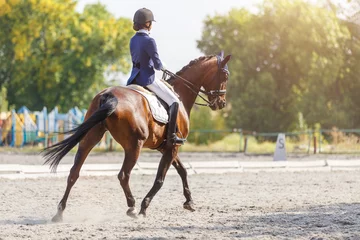 Foto op Canvas Young girl riding horse at dressage advanced test © skumer