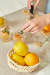 Female hand put rosemary in glasses, making fresh lemonade