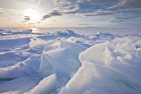 Sunset landscape with glowing hummocky ice on baikal, blue and pink ice is rearing