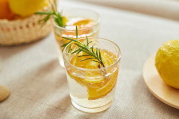 Citrus and rosemary fresh lemonade in glass on a white table at home