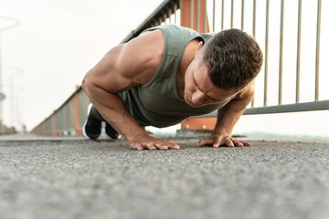 Muscular man is doing push-ups during calisthenic workout on a street
