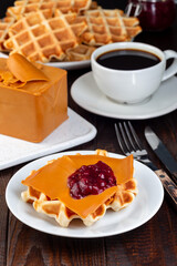 Homemade waffles with norwegian brown cheese and lingon jam, on wooden background, vertical