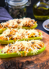 Stuffed zucchini with vegetables and cheese on a wooden board