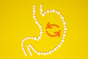 Human stomach from tablets, the process of digestion on a yellow background. The concept of healthy eating, metabolism in the body.