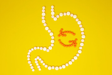 Human stomach from tablets, the process of digestion on a yellow background. The concept of healthy...