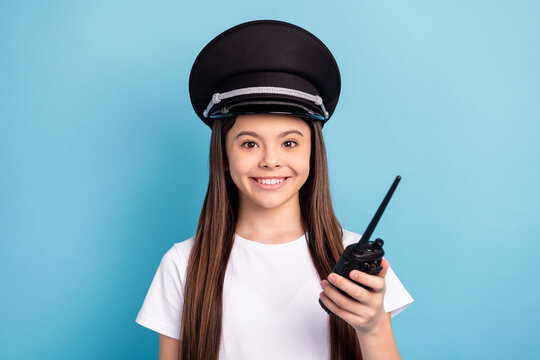 Portrait of attractive cheerful girl wearing hat using radio set talk speak isolated over bright blue color background