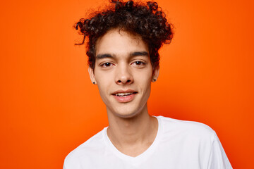 cute guy curly hair emotions grimace studio orange background