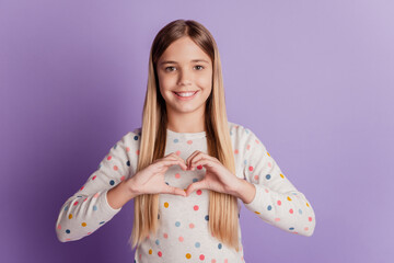 Young kid girl show on chest fingers heart love sign over violet background