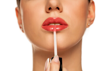 Closeup of woman applying a lip gloss on her lips