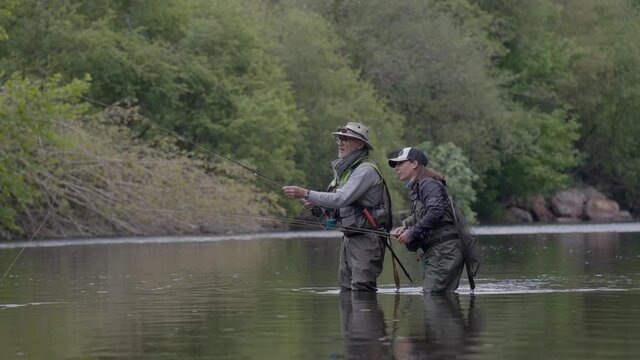 fishing guide with a young woman fly fishing for trout in a clear river