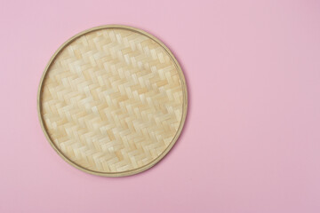 Round wicker straw basket on a pink background. View from above. Decorative interior items. Copy space