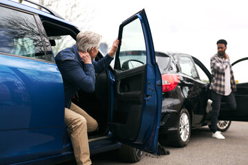 Senior Male And Younger Male Drivers Get Out Of Cars And Inspect Damage After Traffic Accident