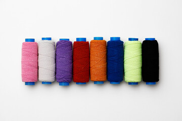 Colored spools of threads on white background