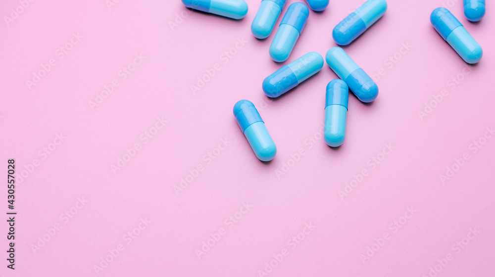 Wall mural blue capsule pills on pink background. blue capsule pills with copy space. pharmaceutical industry. 