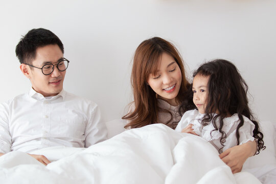 Happy Asian Family Spending A Time Together In Bedroom, Dad And Mom Cheering Their Playful Daughter. 