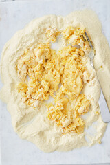 A egg sits in a well formed in the middle of freshly milled flour. The egg and flour will be combined to make fresh pasta.