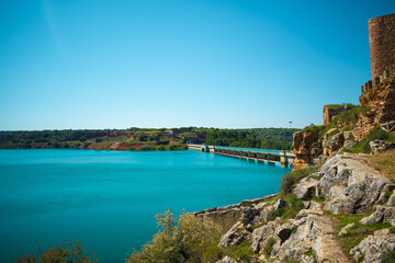 Castle on a hill overlooking beautiful blue lake under clear sky