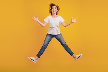 Fototapeta na wymiar Portrait of positive girl jumping raise hands toothy smile on yellow background