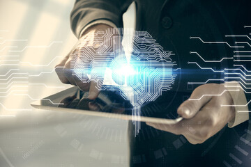 Double exposure of man's hand holding and using a digital device and brain hologram drawing. Data...