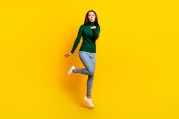Fototapeta na wymiar Full size photo of nice optimistic brunette lady jump blow kiss wear green sweater jeans sneakers isolated on bright yellow color background