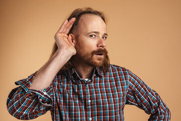 Bearded ginger focused man gesturing and eavesdropping