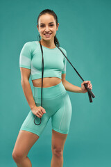 Cheerful young woman with skipping rope posing in studio - obrazy, fototapety, plakaty