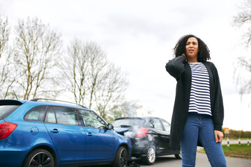 Female Driver With Whiplash Injury Standing By Damaged Car After Road Traffic Accident