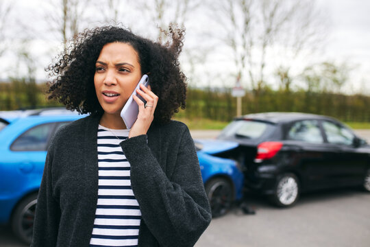 Female Driver Calling Car Insurance Company On Mobile Phone After Road Traffic Accident