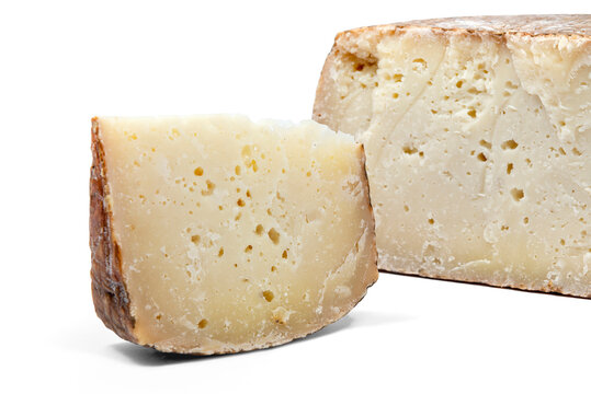 a piece of aged pecorino cheese with cheese wheel in white background