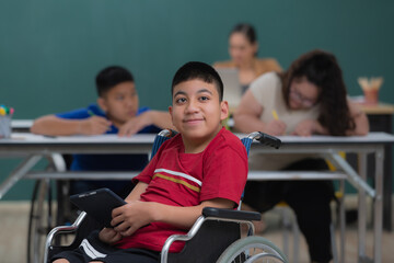 Portrait of young handicapped kid boy sitting on wheelchair and looking to camera with happiness...
